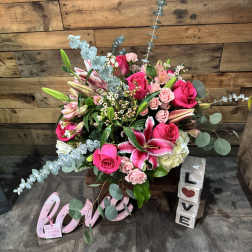 Pink roses and lilies arranged with eucalyptus in a decorative display