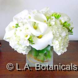 White calla lilies and hydrangeas in a square glass vase