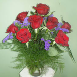 Bouquet of red roses with purple filler in a glass vase