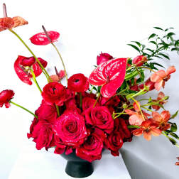 Red roses and anthuriums arranged in a black vase