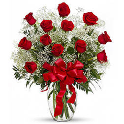 Red roses in a clear glass vase with a red ribbon bow