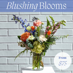 Mixed bouquet in a clear glass vase with blue, pink, orange, and white blooms