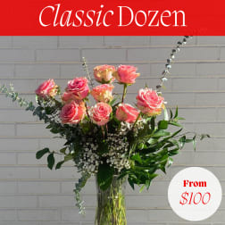 Pink roses arranged in a clear glass vase with greenery