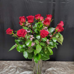Red roses arranged in a clear glass vase with pink filler flowers