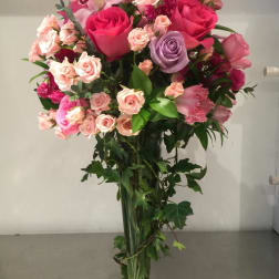 Tall bouquet of pink and lavender roses in a clear glass vase