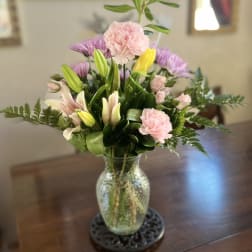 Mixed bouquet of pink and purple flowers in a glass vase