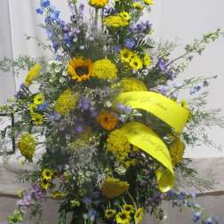 Tall standing floral spray with yellow and blue flowers on a black easel