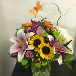 Mixed bouquet in a glass vase with sunflowers, lilies, and roses