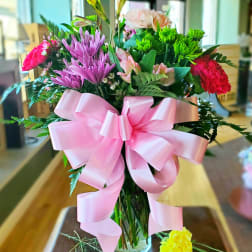 Mixed bouquet in a glass vase with a large pink ribbon