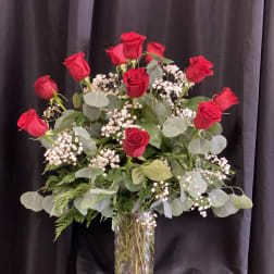 Red roses arranged in a clear glass vase with baby's breath