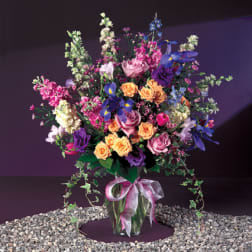 Tall mixed bouquet in a glass vase with a pink ribbon