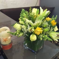 Yellow and white floral arrangement in a square glass vase