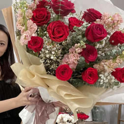 Large bouquet of red roses and pale pink flowers wrapped in white and beige paper