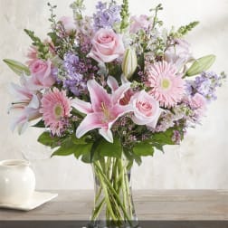 Pink roses, lilies, and gerbera daisies in a clear glass vase