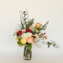 Mixed bouquet in a clear glass jar with roses and white blooms