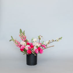 Pink and white floral arrangement in a black cylindrical vase