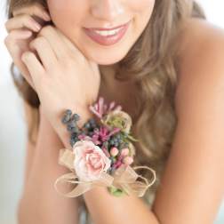 Woman wearing a floral wrist corsage with pink blooms and ribbon