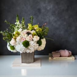 Mixed floral arrangement in a square vase with white and pale pink blooms