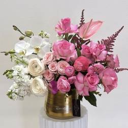Pink roses and white orchids arranged in a gold vase