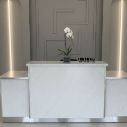 White orchid in a small square vase on a marble reception desk