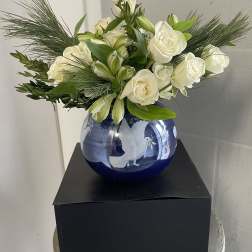 White roses and lilies arranged in a blue glass vase