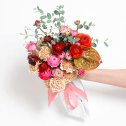 Handheld bouquet of pink, red, and peach flowers with eucalyptus and ribbon