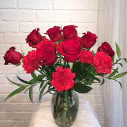 Red roses and carnations in a clear glass vase