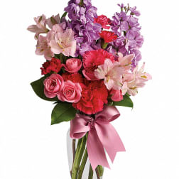 Pink and purple mixed bouquet in a clear glass vase with a satin ribbon