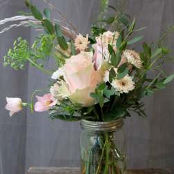 Pink roses and white daisies arranged in a glass jar vase