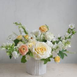 White and peach roses arranged in a white vase