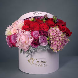 Round box arrangement of red, pink, and purple flowers