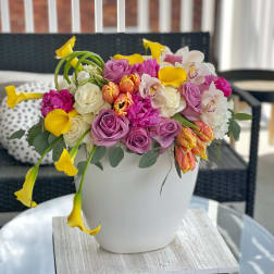 Mixed bouquet of pink, white, and yellow flowers in a white vase