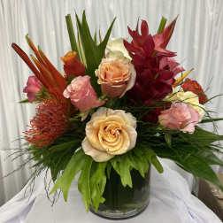 Mixed tropical bouquet with roses in a glass vase