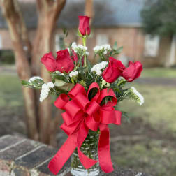 Red roses in a glass vase with a large red ribbon bow