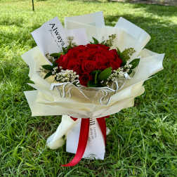 Bouquet of red roses wrapped in white paper with a red ribbon
