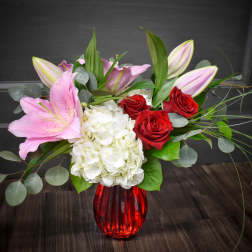 Pink lilies, red roses, and white hydrangea in a red vase