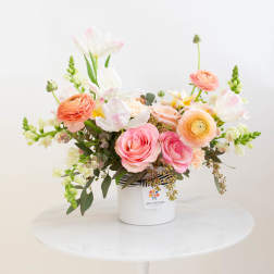 Pink and peach flower arrangement in a white container