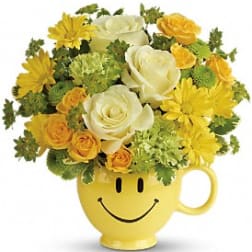 Yellow smiley-face mug holding white and yellow flowers