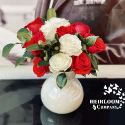 Red and white roses arranged in a white vase
