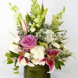 Pink rose and lily arrangement in a green glass vase