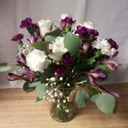 Bouquet of white roses, purple carnations, and alstroemeria in a glass vase