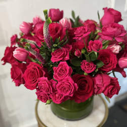 Bright pink roses and tulips arranged in a green vase