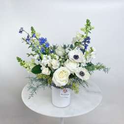 White and blue floral arrangement in a white vase