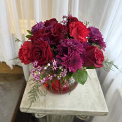 Bouquet of red roses and purple mums in a red vase