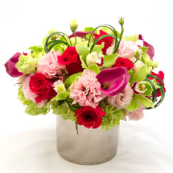 Bouquet of red roses, pink carnations, and green calla lilies in a silver vase