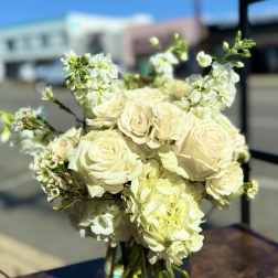 Bouquet of cream roses and white blossoms in a clear glass vase