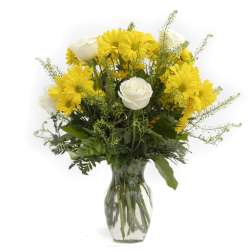 Yellow daisies and white roses in a clear glass vase