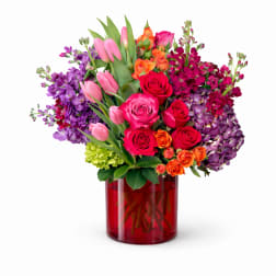 Mixed bouquet of roses and tulips in a red glass vase