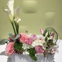 Pink and white floral arrangement in a white rectangular container