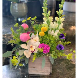 Mixed floral arrangement in a wooden box with pink, white, yellow, and purple blooms